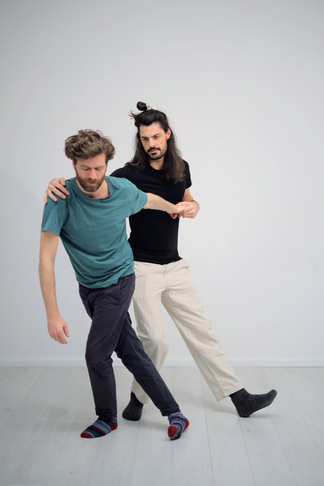 Immanuel guiding a standing client through slow movement, supporting from behind