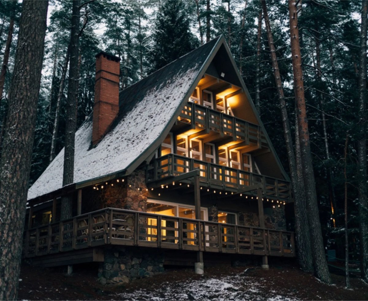 The A-frame house glowing warmly at dusk among the pines
