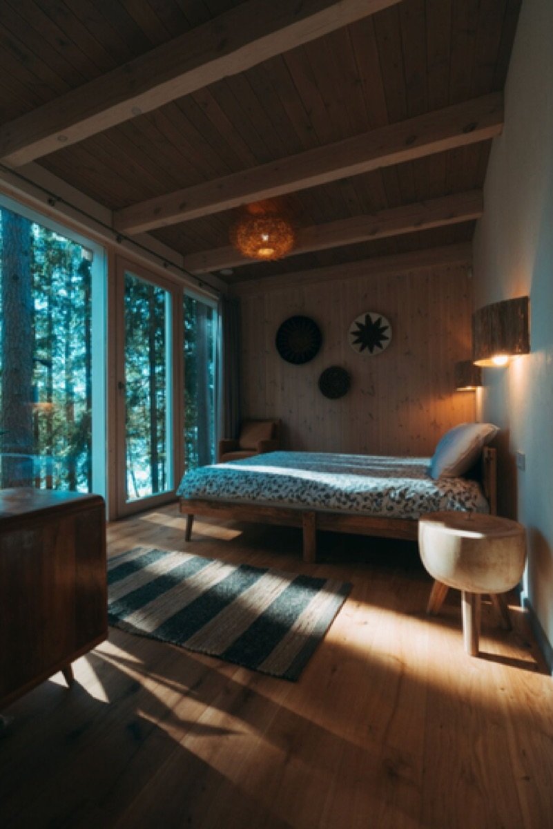 En-suite bedroom with floor-to-ceiling forest windows